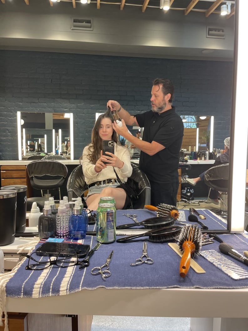 author in a salon chair while a stylist lifts her roots