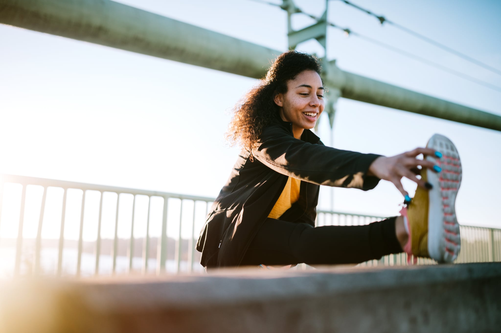 A young mixed race woman stretches before an early jog in the city of Tacoma, Washington.  Her running takes her across the Tacoma Narrows bridge, with a running path spanning the Puget Sound from Tacoma to Gig Harbor.