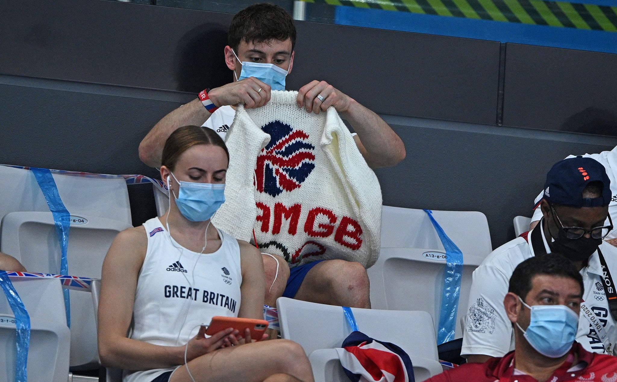 TOPSHOT - British diver Thomas Daley sits with his knitting as he watches divers in the preliminary round of the men's 3m springboard diving event during the Tokyo 2020 Olympic Games at the Tokyo Aquatics Centre in Tokyo on August 2, 2021. (Photo by Oli SCARFF / AFP) (Photo by OLI SCARFF/AFP via Getty Images)