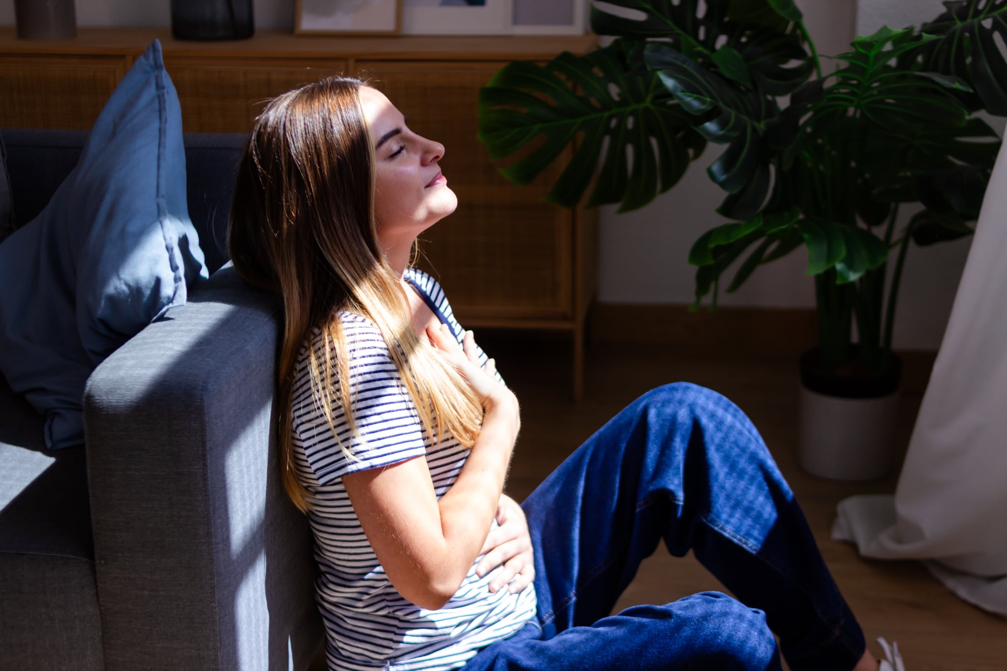 Young woman is feeling calm and relaxed while practicing breathing at home.
