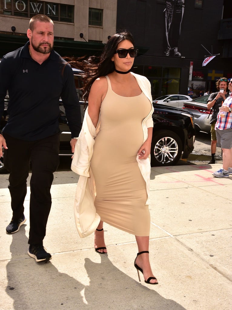 Kim stepped out in a cream body-con tank dress that hugged her growing bump. She covered up with a silk kimono-style robe and accented her look with ankle-strap heels and a thick black choker, giving off subtle '90s vibes.