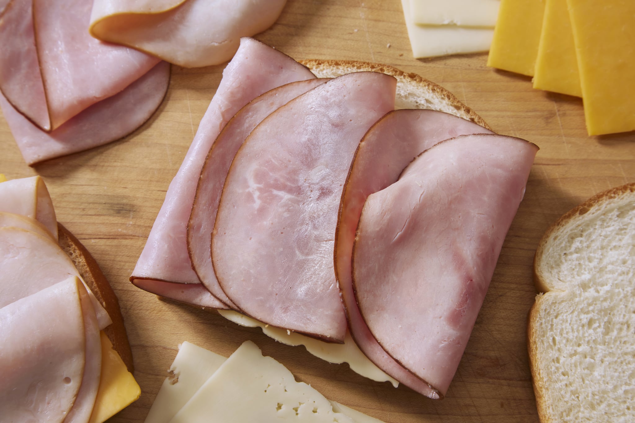 Slices of bread with Black Forest Ham, Smoked Turkey Breast, Cheddar and Swiss Cheese — deli meats that are possible sources of listeria — on them