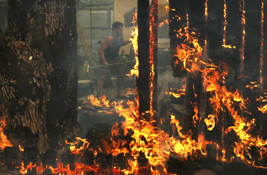 A resident struggles to contain flames in his home.