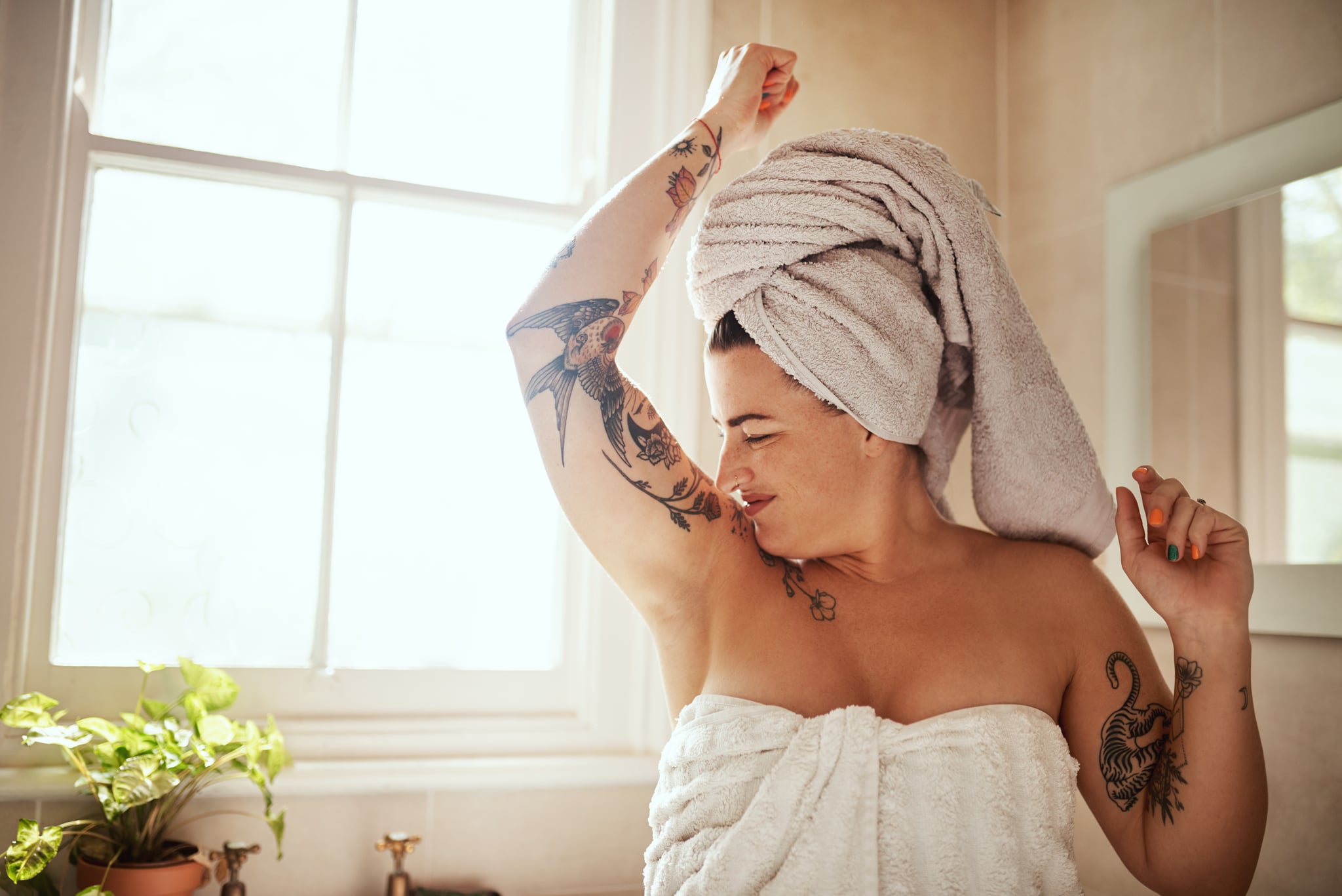 Woman smelling her armpits in her bathroom.