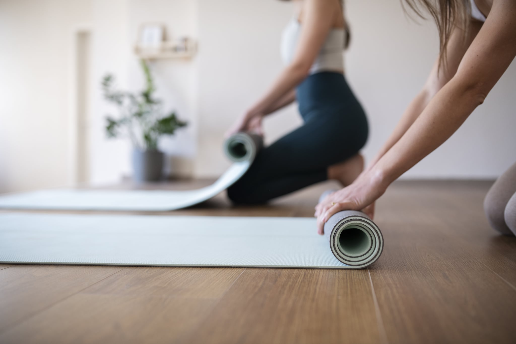 Unrecognisable young women rolling up their yoga mat after exersice.
