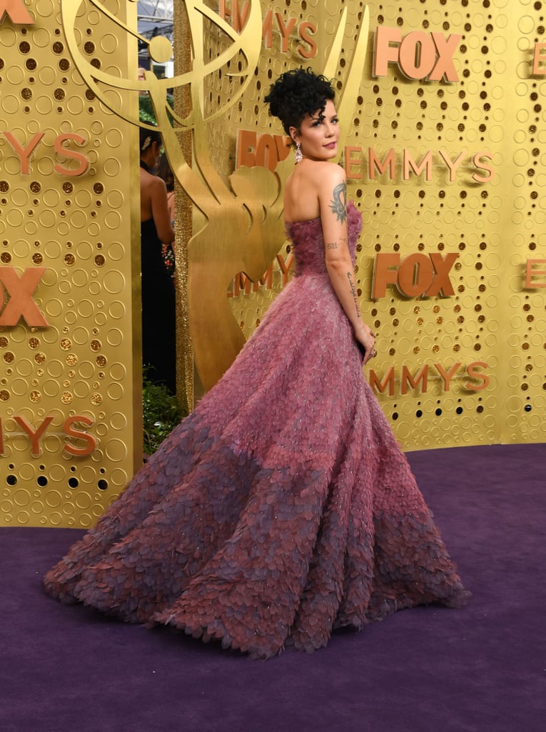 Halsey looked like a real-life princess when she stepped out at the 2019 Emmy Awards in LA on Sunday night. Dressed in a gorgeous pink and purple gown, the 24-year-old singer was practically glowing as she marked her first time at the ceremony. While Halsey isn't nominated for any awards tonight, she is set to take the stage for a special in memoriam performance. 
Halsey's big night comes a little over a week after she attended Rihanna's Savage x Fenty show in NYC, where she avoided a potentially awkward run-in with her ex G-Eazy. She also performed at the iHeartRadio Music Festival in Las Vegas on Friday night and recently released her new single, "Graveyard." Yep, it's definitely been a busy month for Halsey. See more of her glamorous Emmys night ahead!