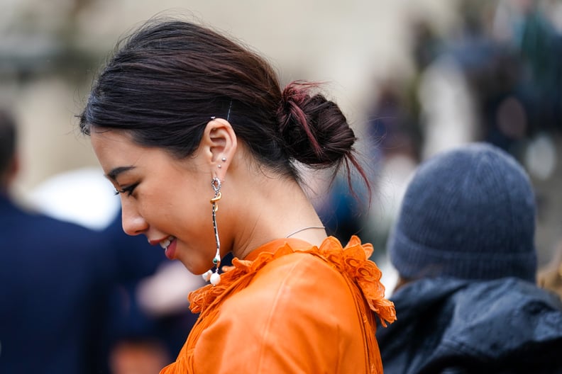 PARIS, FRANCE - FEBRUARY 27: A guest wears an orange dress with embroidery on the collar, long earrings, outside Chloe, during Paris Fashion Week - Womenswear Fall/Winter 2020/2021, on February 27, 2020 in Paris, France. (Photo by Edward Berthelot/Getty I