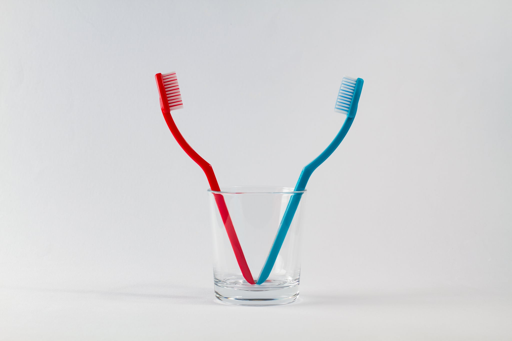 a red and blue toothbrush in a glass