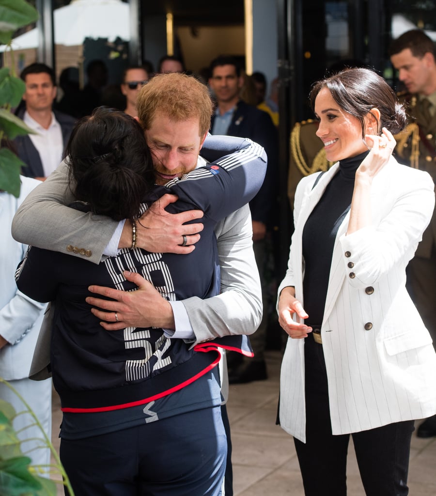 . . . and Prince Harry has become quite the hugger, here seen embracing an athlete at a reception in Australia.