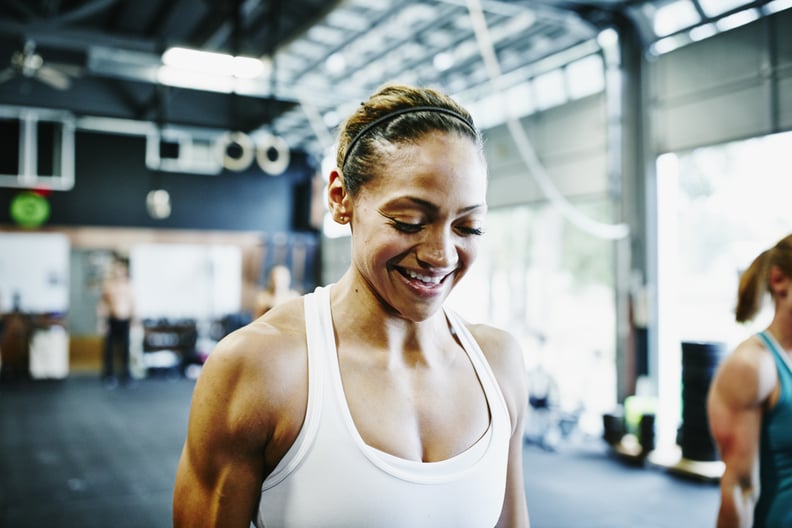 Smiling woman carrying kettlebells during workout in gym