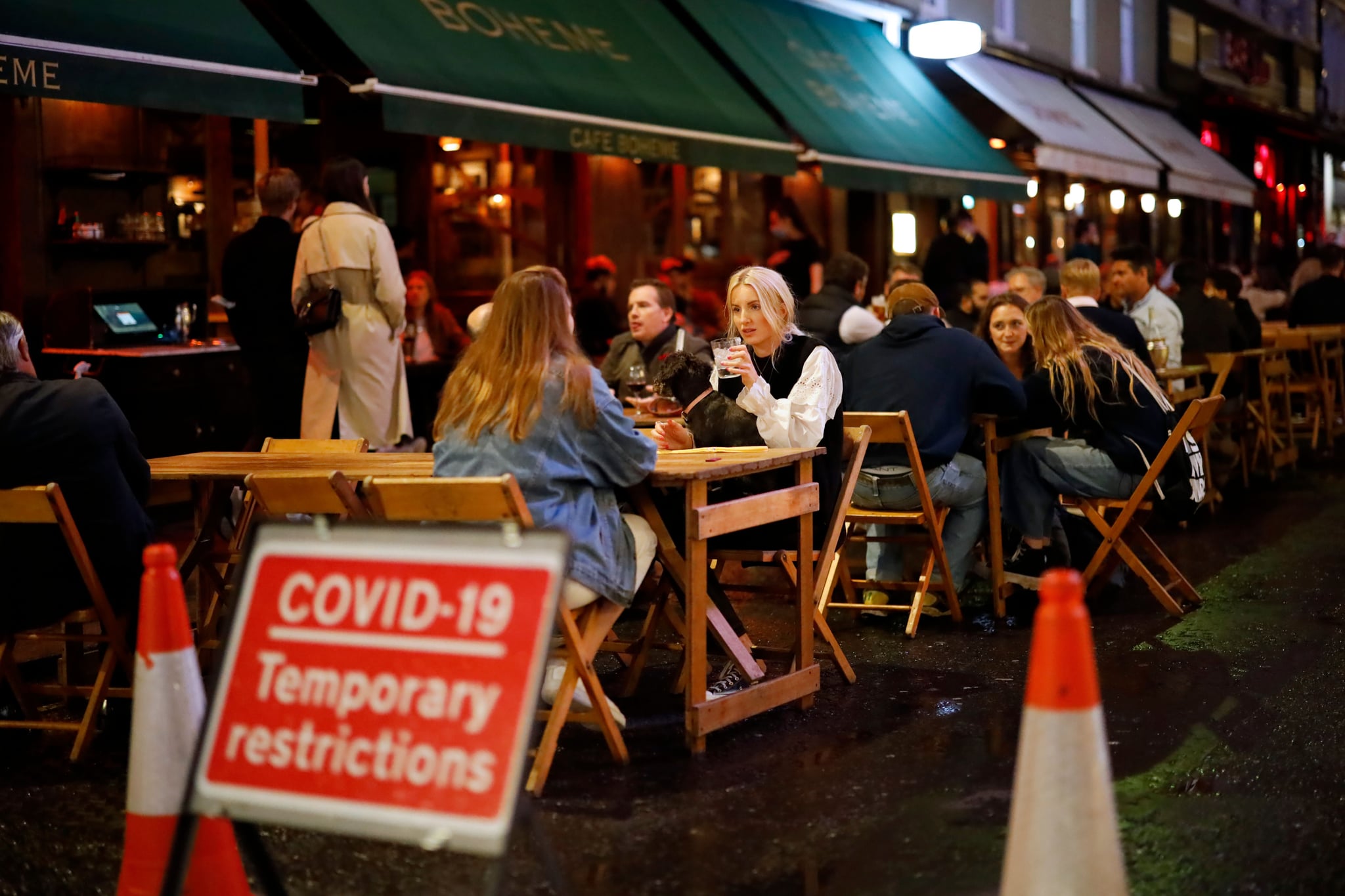 People drink at the outside tables of a cafe in Soho, in central London on September 23, 2020. - Britain on Tuesday tightened restrictions to stem a surge of coronavirus cases, ordering pubs to close early and advising people to go back to working from home to prevent a second national lockdown. (Photo by Tolga Akmen / AFP) (Photo by TOLGA AKMEN/AFP via Getty Images)