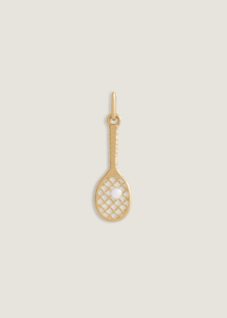 Kinn x Sunset Tennis Club Ball And Racquet Charm Pearl ($280)
For a more subtle nod to tenniscore, add this sweet charm to your necklace or bracelet. The tiny tennis racket, part of a collab between Kinn Studio and Sunset Tennis Club, is adorned with a little pearl ball, the sweetest touch that will definitely earn some double takes. And it's 14k solid gold, so it can withstand your sweatiest matches and the post-game shower, all without tarnishing.