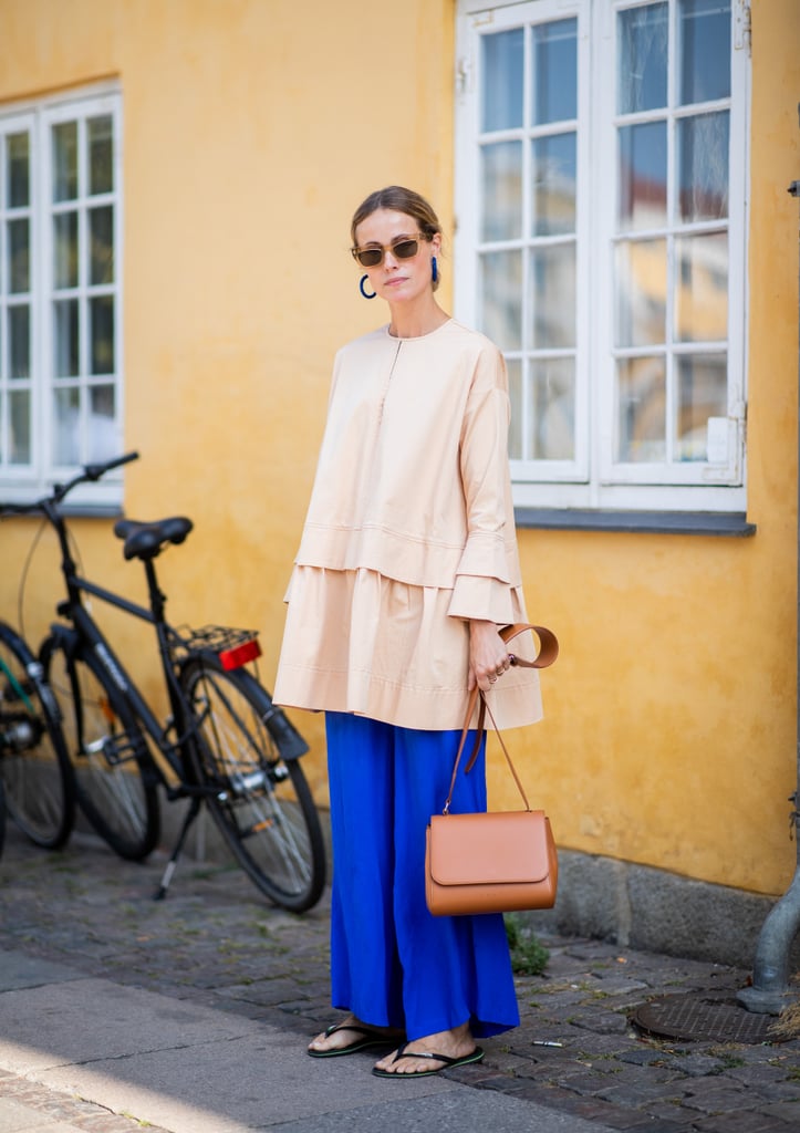 Styling a black pair of Havaianas with an oversize shirt and blue pants.