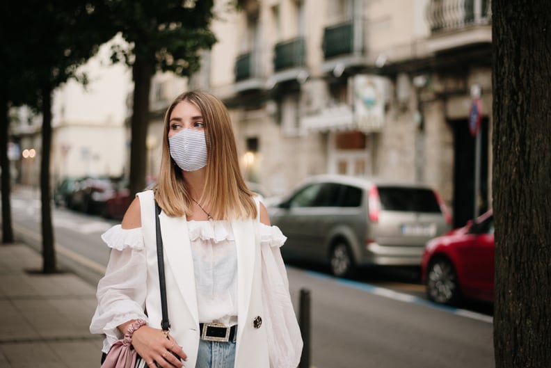 A young woman in a city street, wearing a protective face mask during the COVID-19 pandemic