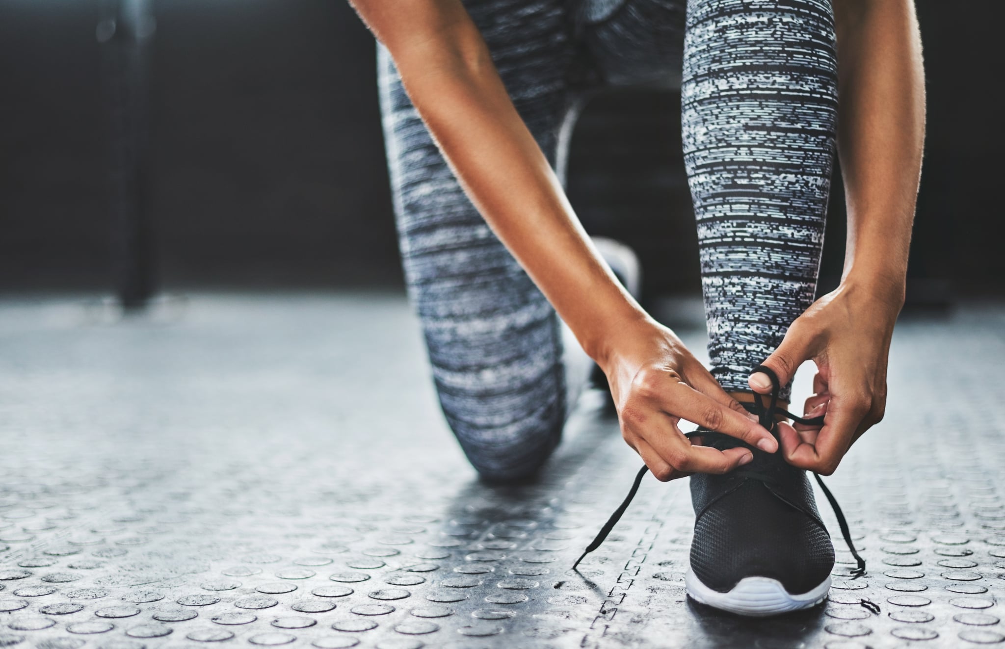 Cropped shot of a woman tying her shoelaces in a gym