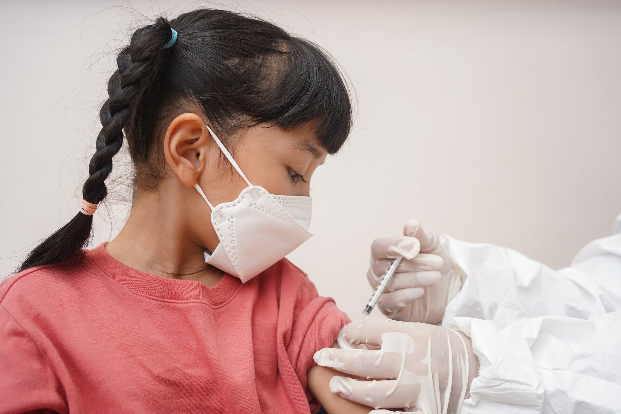 Little patient in face mask receiving coronavirus or flu vaccine shot from nurse at hospital.Vaccination, immunization, disease prevention concept.