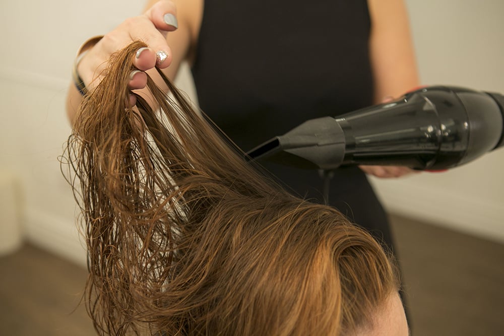 "Make sure your hair is 90 percent dry before you use a brush," Halpin says. "It'll make it easier for you to work with the brush later." She used her hands to get most of the moisture out of our model's hair. You can also turn your head upside down while you're rough-drying to get added lift at the roots.
If you have thicker, curlier hair, Halpin says you'll actually need to start drying your hair with a brush from the start to get that sleek blowout.
Source: Caroline Voagen Nelson