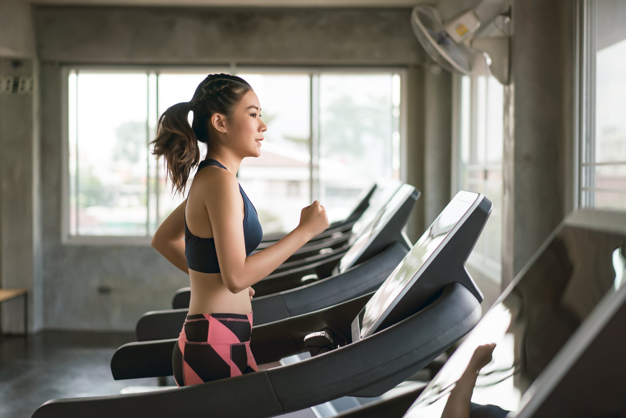 Young women in sportswear running on treadmill at gym