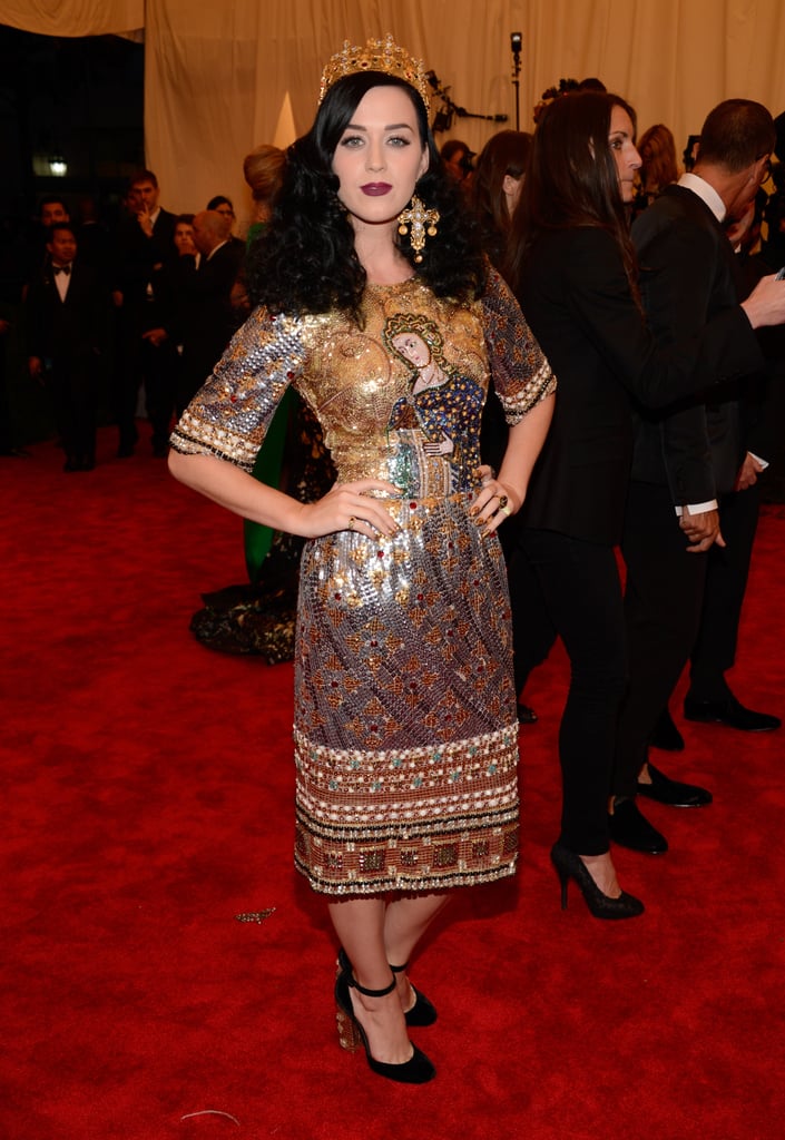 Posing in an opulent Dolce & Gabbana sheath accessorized with raven-hued locks, a guilded crown, and statement crucifix earrings, Ms. Perry's 2013 Met Gala look was all about dark decadence.