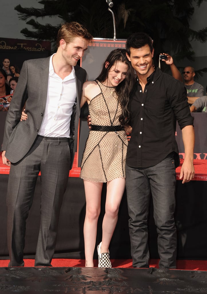 It's a big day for Twilight fans — Robert, Kristen, and Taylor's handprints were laid down in cement outside Grauman's Chinese Theatre this morning! While Rob and Taylor were in suits, Kristen sparkled in a Marios Schwab dress. The heat was a little much for Rob, who joked that he wished he'd remembered the LA temperatures and picked a different outfit. Jimmy Kimmel introduced the trio, getting some hopes up by saying Taylor would also put his abs into the cement! Along with plenty of fans in the crowd, Rob's parents were on hand to witness the ceremony as well. 
It was a major milestone for the three leads in the franchise, who will all be busy in the coming weeks in the run-up to Breaking Dawn Part 1's release on Nov. 18. Robert and Taylor have already started making the late night talk show rounds, with Robert visiting Jimmy Kimmel Live and Taylor doing The Tonight Show just yesterday. Robert also linked up with Ashley Greene for a couple of early premieres in Europe last week.
Now that Robert, Kristen, and Taylor have reunited for their final press push, all eyes will be on Mr. Pattinson and Ms. Stewart for any signs of affection. Kristen finally admitted to their relationship in an interview in GQ UK, saying, "So much of my life is so easily Googled. I mean, it’s like, come on guys, it’s so obvious . . . It’s just one of those things. I’m selfish. I’m like, 'That’s mine!' And I like to keep whatever is mine remaining that way." With only one more movie to come in the franchise, these will be among the last photocalls and screenings Robert, Kristen, and Taylor do with their many cast mates.
