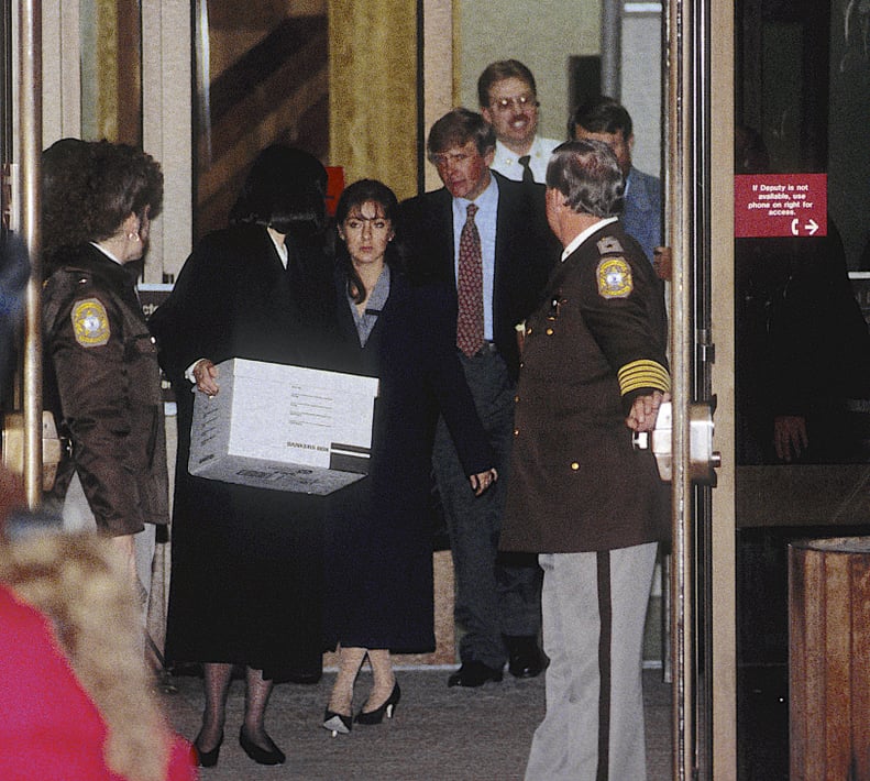 On the second day of her trial, the accused, Lorena Bobbitt (center), and her lawyers, Lisa Kemler (with box), Blair Howard (red tie), and James Lowe (right, mostly obscured behind deputy), leave the Prince William County Courthouse, Manassas, Virginia, J