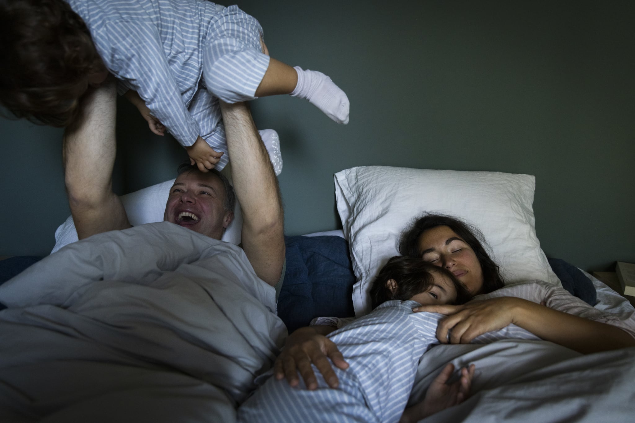 A photo shows a dad, mom, and two kids sleeping in the same bed.
