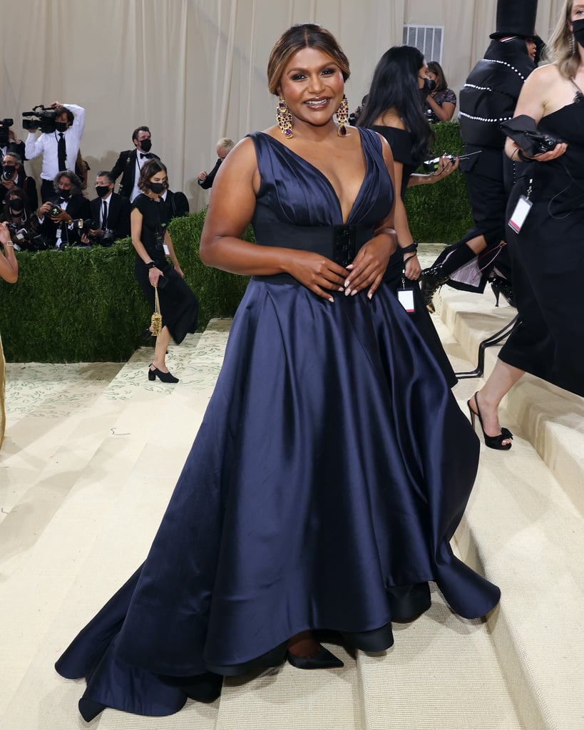 As a friend of the Tory Burch fashion house, Kaling attended the 2021 Met Gala with the brand, opting for complete sophistication in a midnight-navy gown with a plunging neckline and thick corset belt to add structure. She finished the look with satin pumps and architectural gold earrings with amethyst stones.