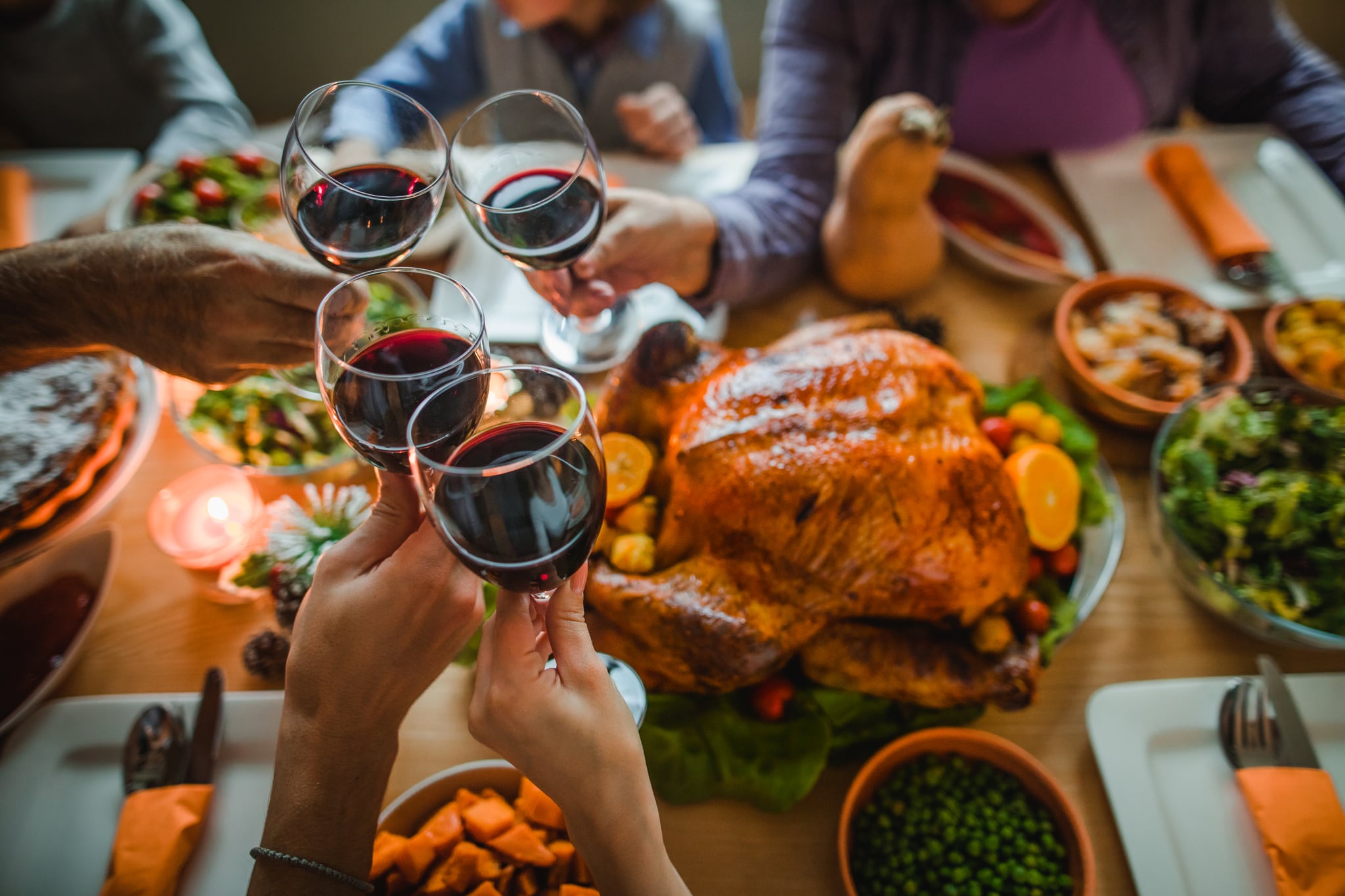 Group of unrecognisable people toasting with wine during Thanksgiving dinner at dining table.