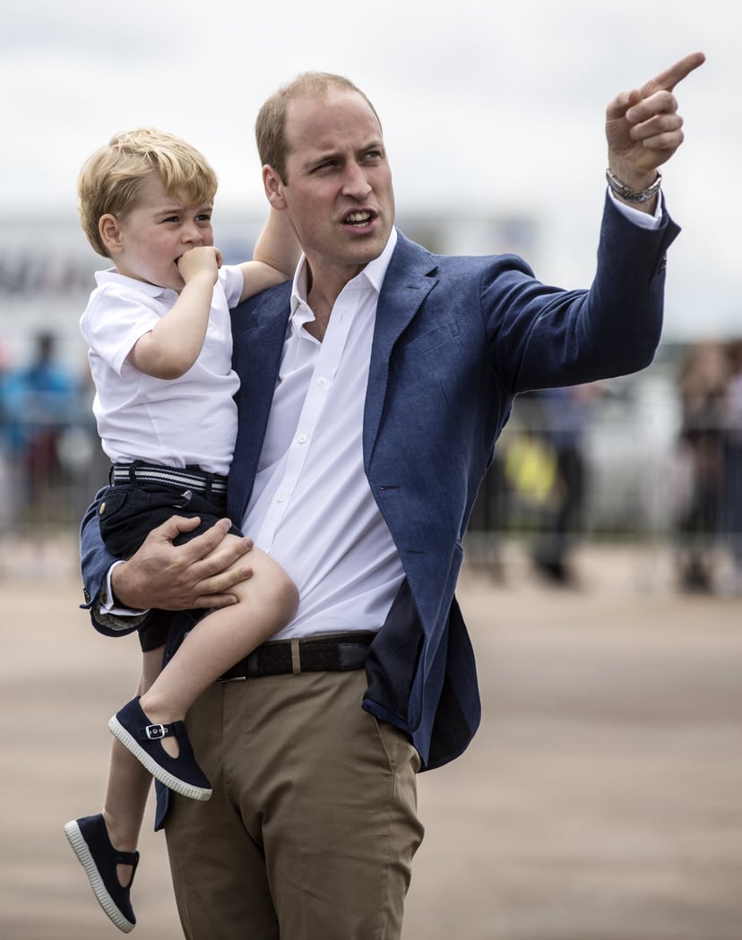 Britain's Prince George is carried by his father Prince William as they visit the Royal International Air Tattoo at RAF Fairford in western England, on July 8, 2016. / AFP / POOL / RICHARD POHLE        (Photo credit should read RICHARD POHLE/AFP/Getty Ima