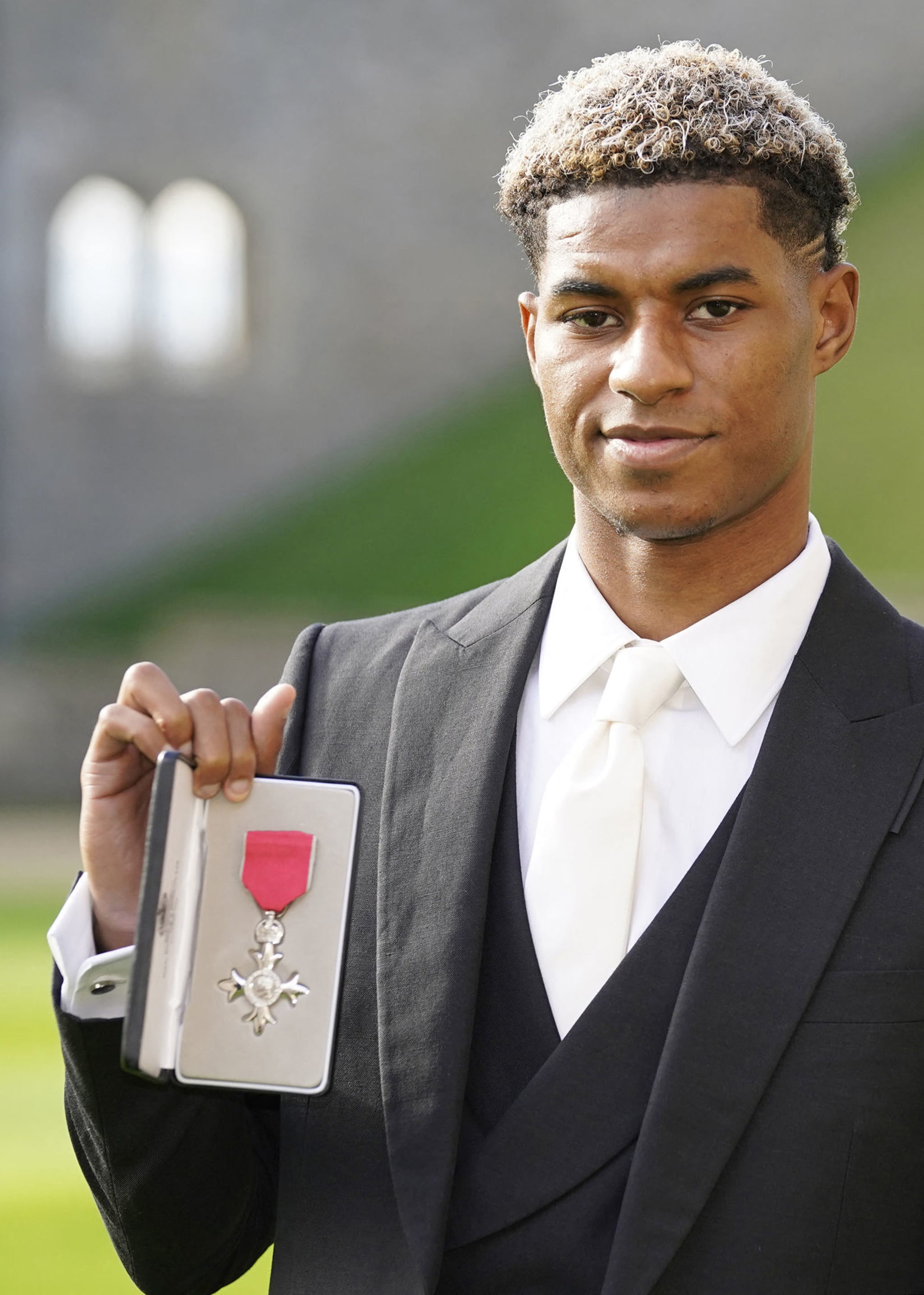 Manchester United and England footballer Marcus Rashford poses with his medal after being appointed a Member of the Order of the British Empire (MBE) for services to Vulnerable Children in the UK during the Covid-19 pandemic, following an investiture ceremony at Windsor Castle in Windsor, west of London on November 9, 2021. (Photo by Andrew Matthews / POOL / AFP) (Photo by ANDREW MATTHEWS/POOL/AFP via Getty Images)