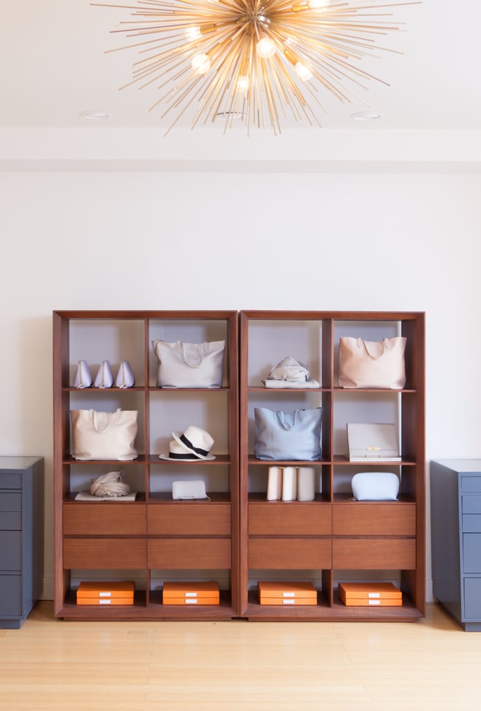 A mid-century modern bookcase is the perfect spot for accessories, like hats and tote bags. Cuyana's signature orange boxes add the perfect pop of color on the bottom shelf.