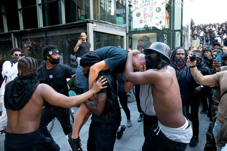 LONDON, UNITED KINGDOM - JUNE 13: A group of men including Patrick Hutchinson (carrying the man) help an injured man away after he was allegedly attacked by some of the crowd of protesters on the Southbank near Waterloo station on June 13, 2020 in London,