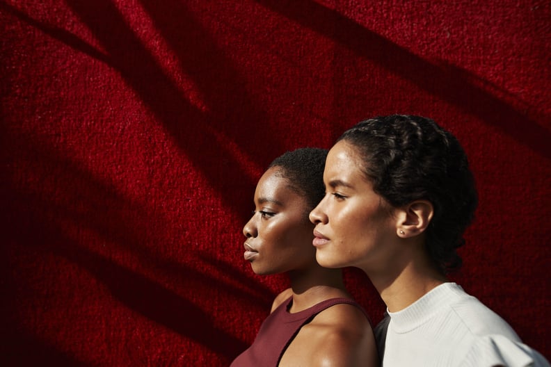 Side view of beautiful women standing against red wall