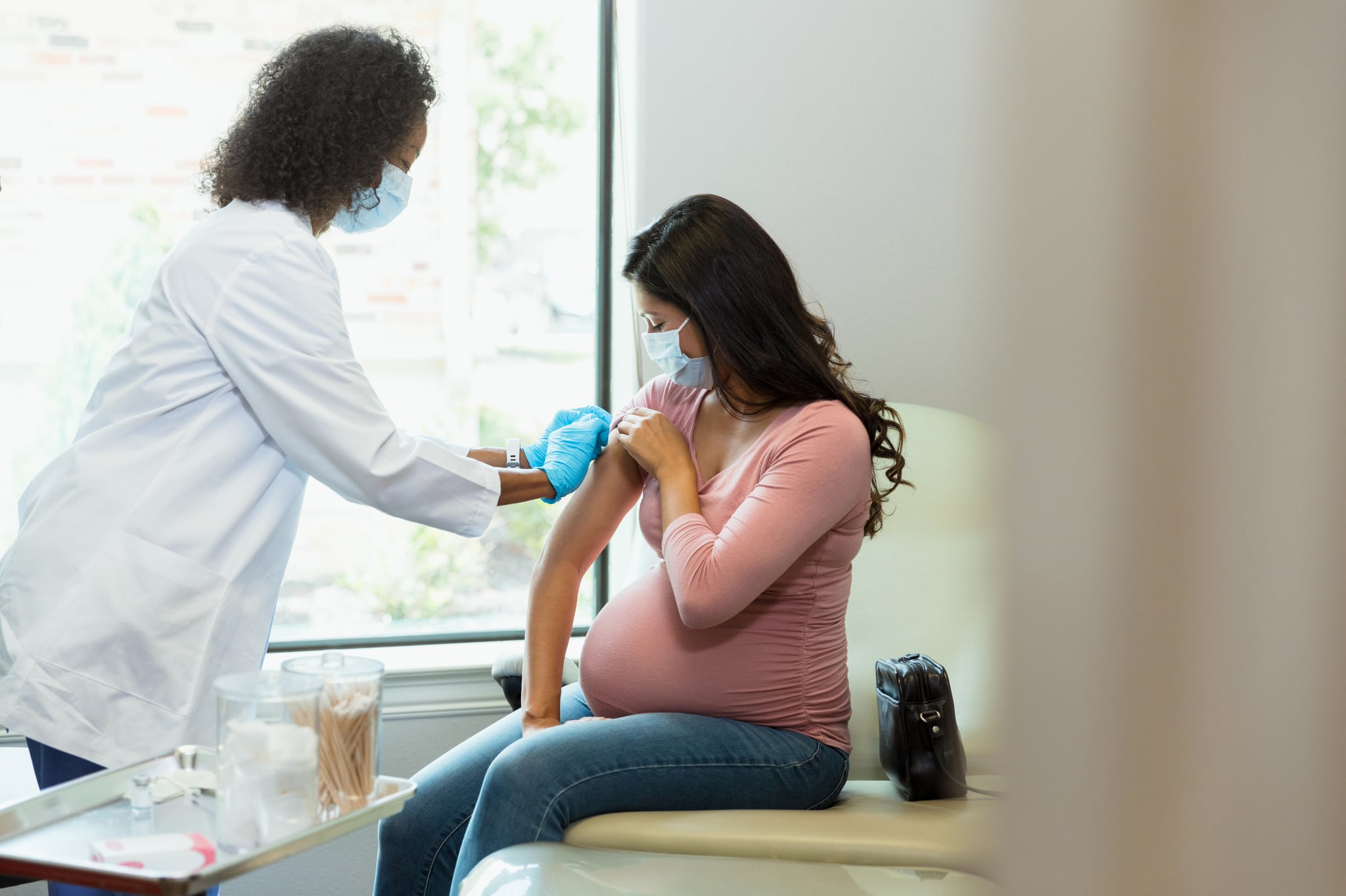 During COVID-19, the pregnant woman receives a vaccine at the doctor's office.