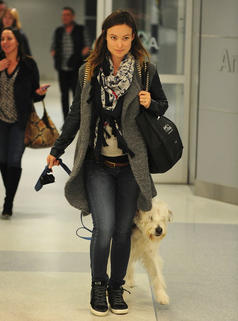 Olivia Wilde layered up in a cozy coat, sweater, and fringed scarf.