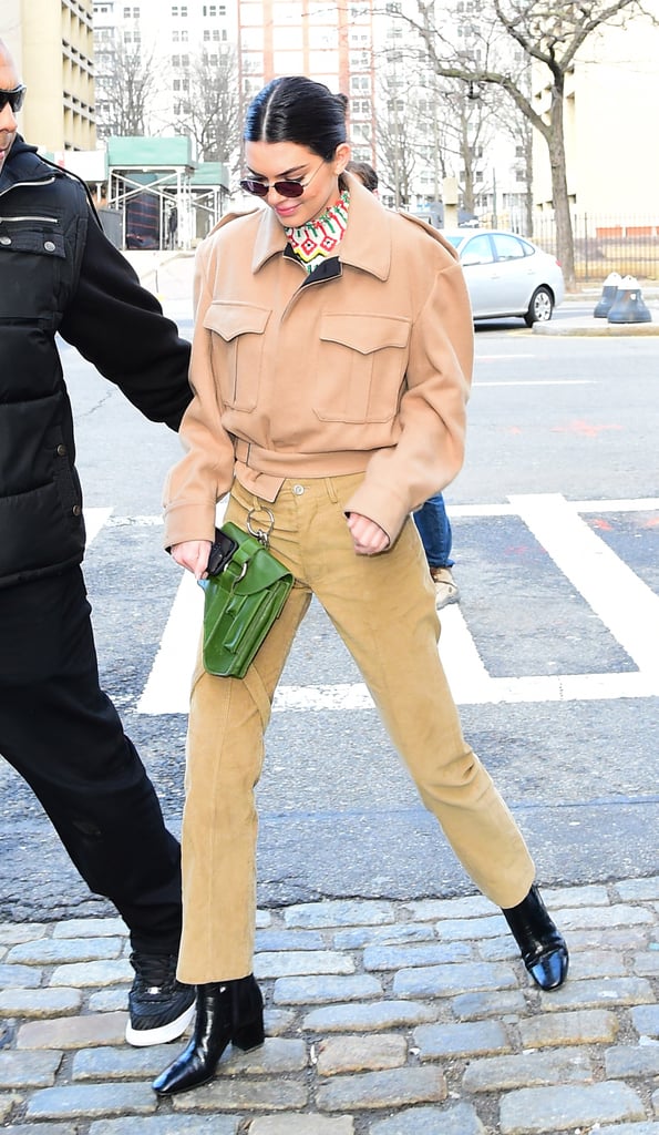 Kendall stepped out in neutral Winter Private Policy basics, including a camel-colored coat and trousers. She wore patent black booties and a green belt buckle bag, and a colorful graphic-print turtleneck stuck out from underneath.