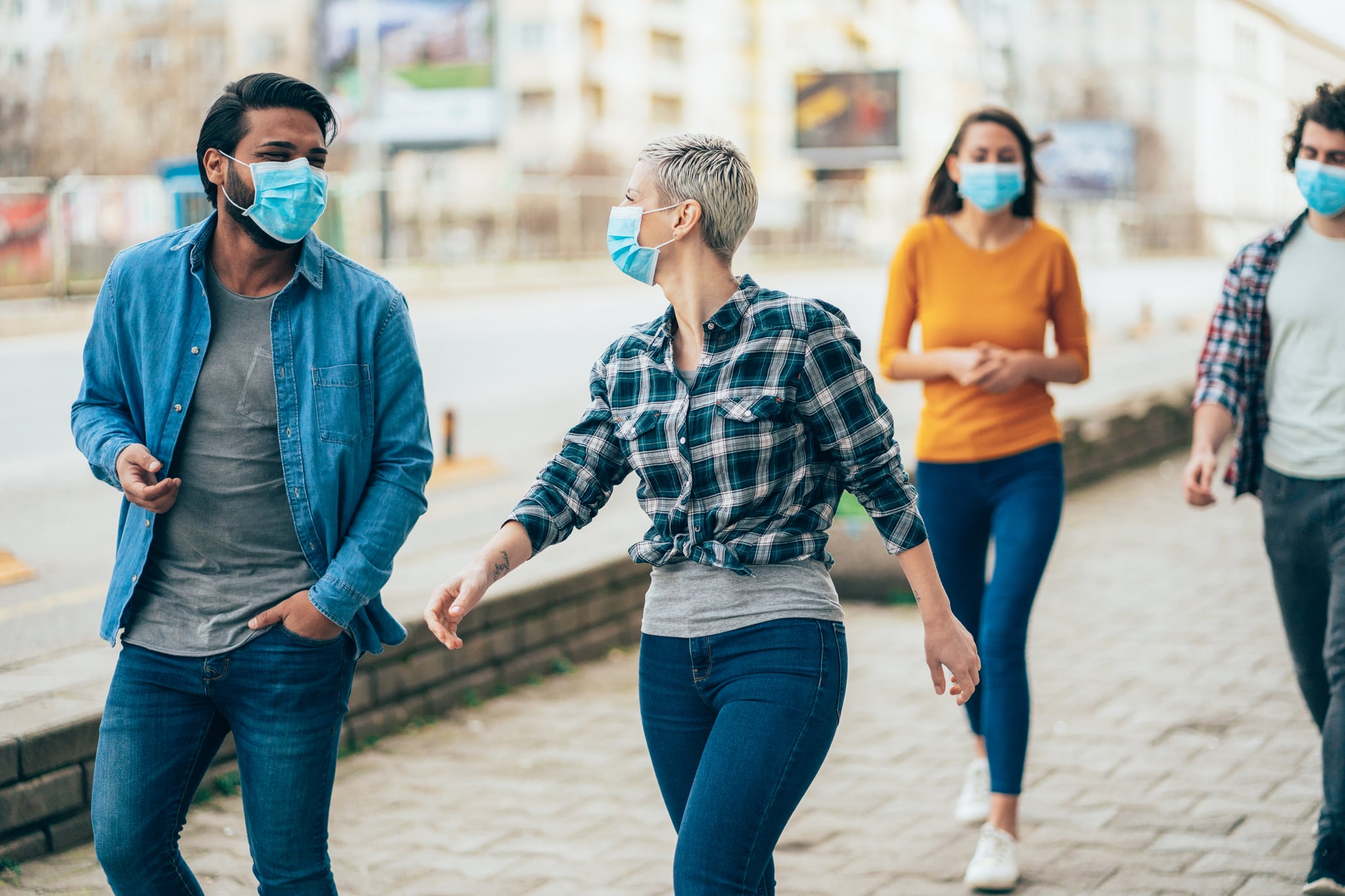 Young people meet in quarantine outside on the city street wearing face protective mask to prevent Coronavirus and anti-smog