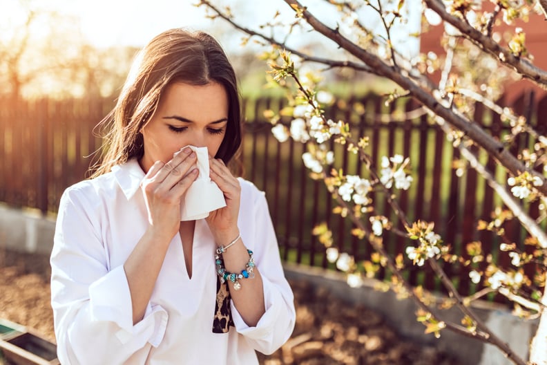有吸引力的年轻成年女性在户外咳嗽和打喷嚏。病人过敏或病毒influenca概念。