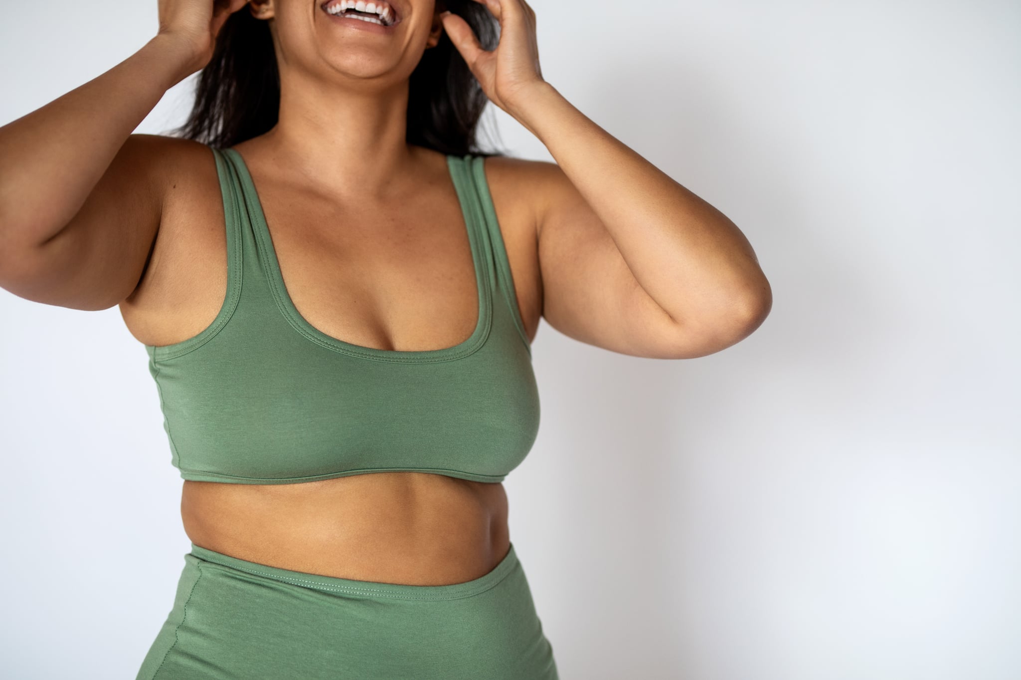 Cropped shot of a chubby woman in underwear on white background. Oversized woman wearing lingerie smiling.