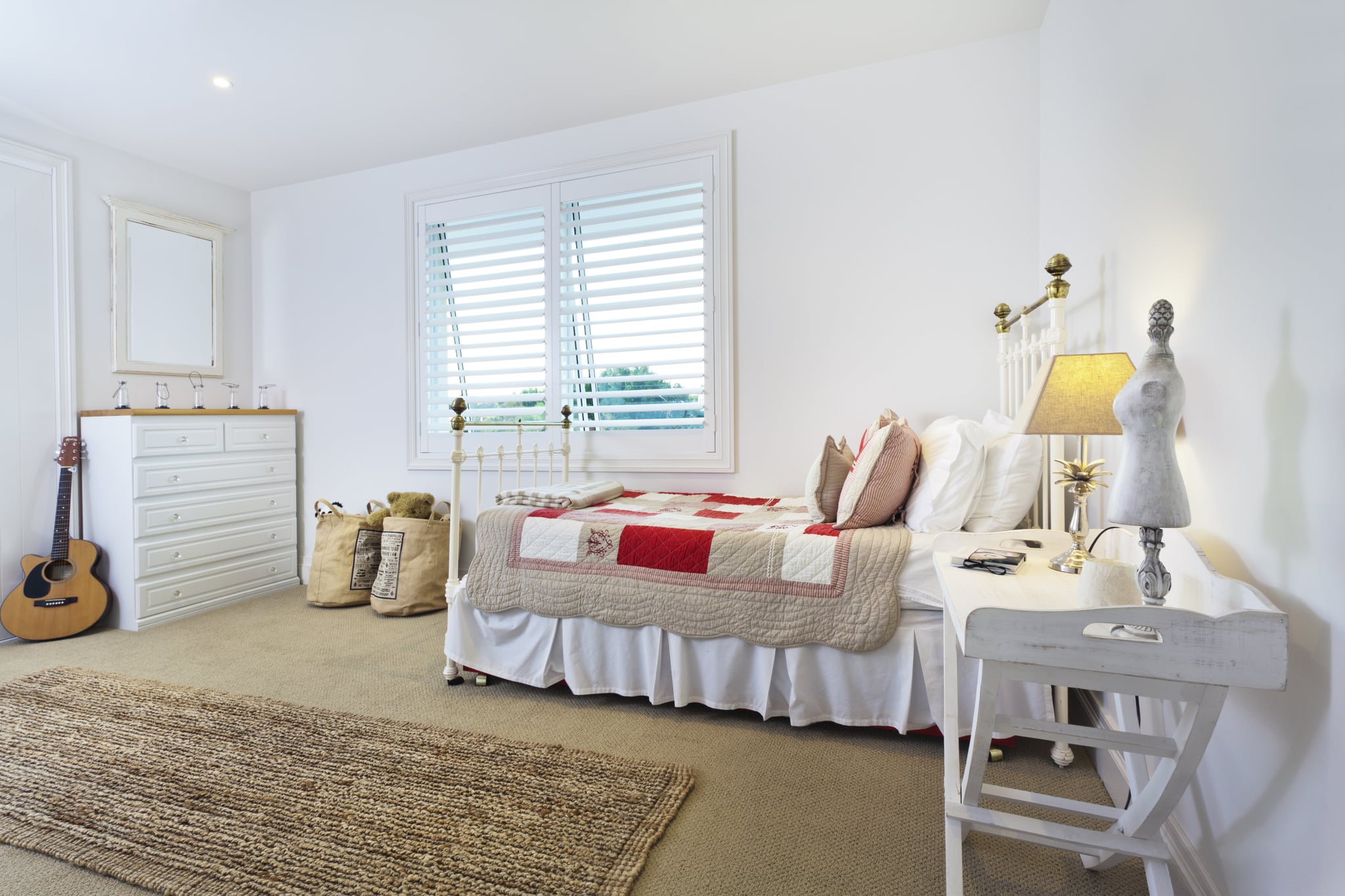  A bedroom with a bed, a dresser, a nightstand, and a rug on the floor looks clean and organized.