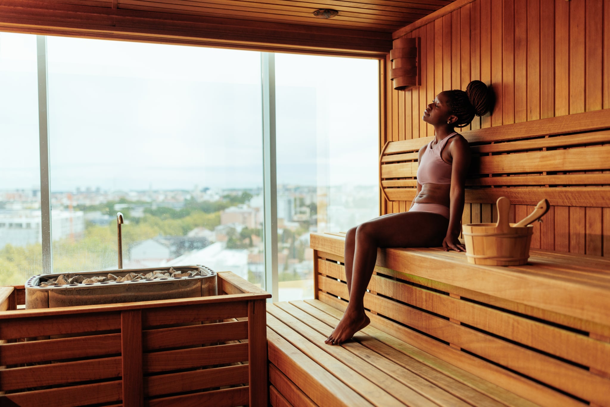 A young Black woman sitting on the bench in sauna relaxing. A young Black woman sitting on the bench in sauna relaxing.