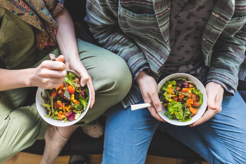 Couple eating salad on the sofa as part of a fertility diet.