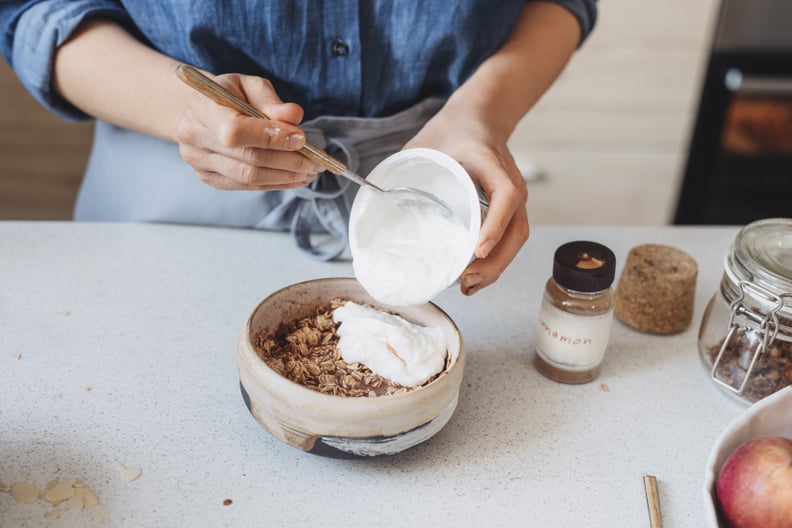 Making breakfast: unrecognizable woman adding greek yogurt to oatmeal: is greek yogurt healthy?