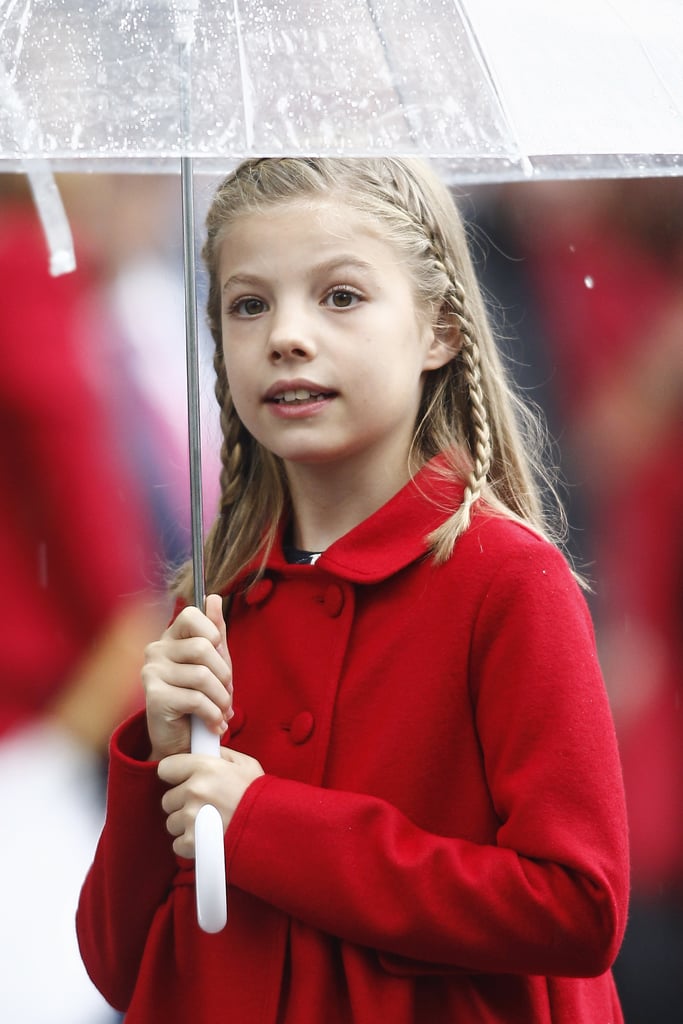 Infanta Sofía protects herself from the rain on Spain's National Day.