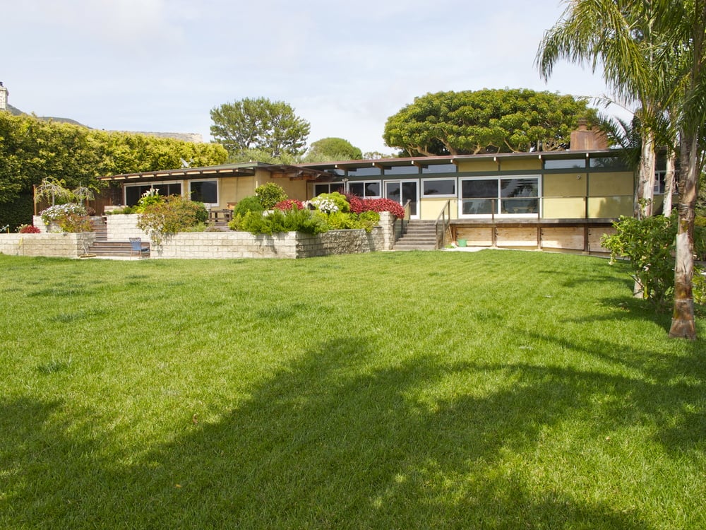 The lush property boasts green lawns, fruit trees, and a horse corral.