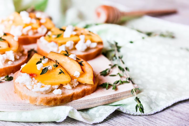 Homemade Bruschetta with nectarines, salted feta cheese, dried thyme and honey on a wooden board, selective focus