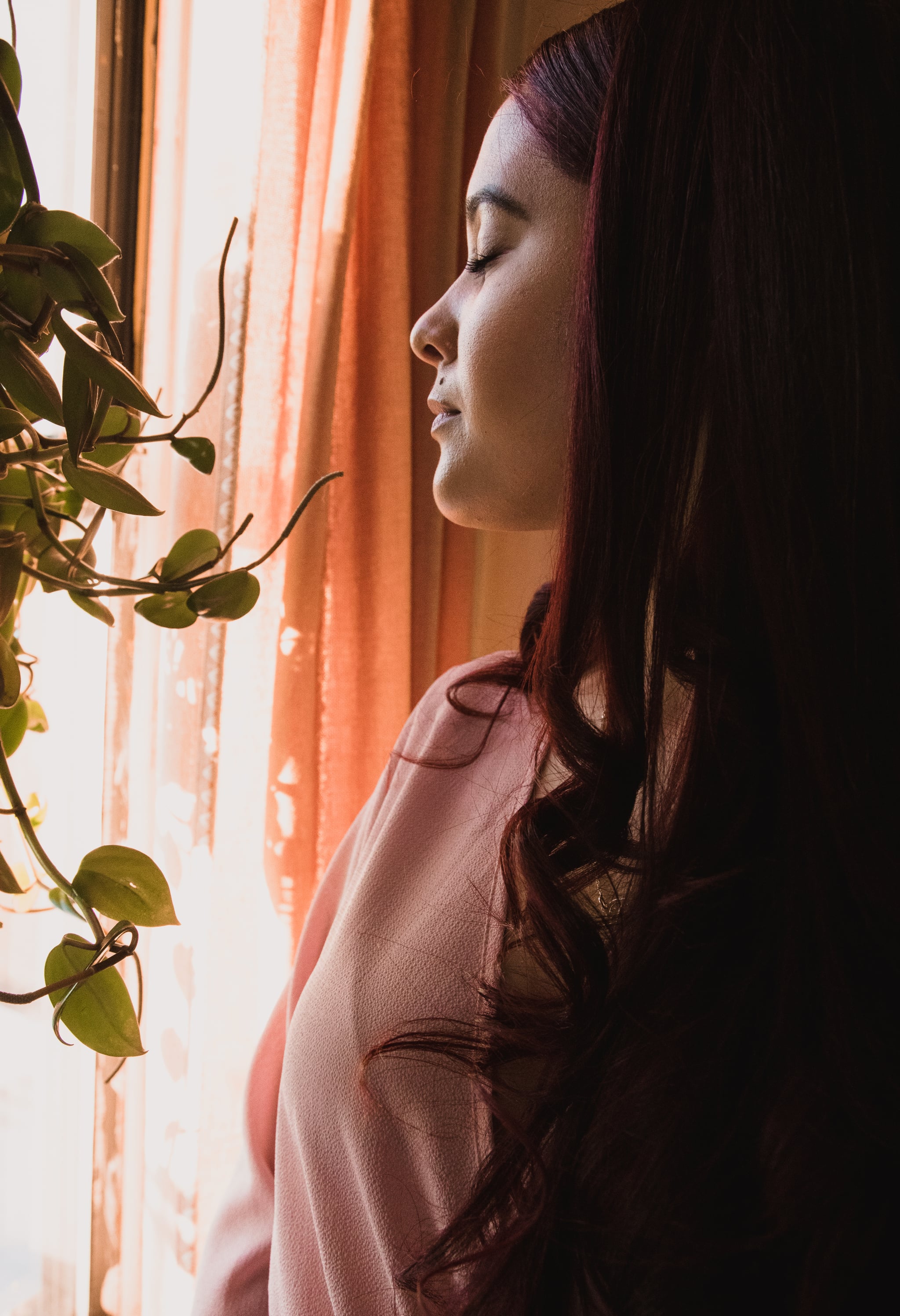 Woman by the window. Light skinned Latina woman with eyes close standing by the window of a bedroom.