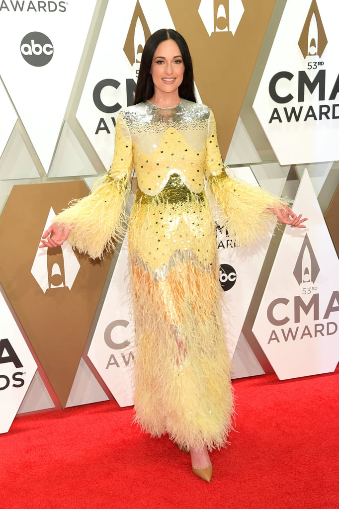 Kacey Musgraves brought the sunshine to the CMA Awards red carpet on Wednesday night. The "Slow Burn" singer looked absolutely stunning in a feathery pastel yellow Valentino gown with metallic detailing. The long-sleeve ensemble perfectly complemented her pal Gigi Hadid's all-white outfit, and the two made a picturesque pair posing together for photos.
Kacey's stylist, Erica Cloud, shared behind the scenes snaps of Kacey's look which helped us nail the exact details. Her dress is from Valentino's Spring Summer 2020 Womenswear line, which we last saw on the runway back in September during Paris Fashion Week. Kacey is certainly no stranger to the famed designer either — in fact, she wore a Valentino gown to the Grammys earlier this year.

    Related:

            
            
                                    
                            

            Yeehaw Queen? Kacey Musgraves Is More Like a Fashion Queen in These Iconic Looks