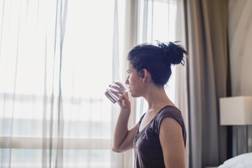 Young woman drinking water in the bedroom