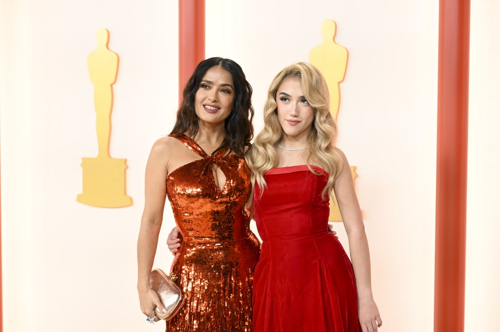 Many dream of having access to a Hollywood veteran's red carpet wardrobe. For Salma Hayek's daughter Valentina Pinault, that's her reality. Wearing one of her mom's archival pieces, the 15-year-old joined Hayek on the Oscars red carpet on March 12 as her date. The "Magic Mike's Last Dance" star sparkled in a custom Gucci dress with a halter neckline and a fringe train, while her daughter matched in a strapless A-line gown by Isaac Mizrahi.
The 56-year-old actor and producer originally wore the velvet dress over 25 years ago, for the Fire & Ice Ball, a charity event, back in 1997. At the time, Hayek completed the look with a matching red shawl draped over her arms, a stacked diamond necklace, a sequined red purse, and a classic red lip to tie it all together. 
With help from Hayek's stylist Rebecca Corbin-Murray, Pinault modernized the gown for the 2023 Oscars with a simple tennis necklace and earrings from Anita Ko, a silver bag, and neutral makeup. Though the dress may belong to Hayek, it certainly appears to be made for the stylish teen, who's following in her mom's footsteps as an aspiring actor and director. 
The mother-daughter duo stopped by the Vanity Fair afterparty later in the night, swapping their matching red ensembles for complementary pink and silver gowns. Hayek wore another dazzling Gucci creation, this time with a plunging neckline and a lace-up leg slit. Pinault, on the other hand, changed into a romantic rose-colored gown with draped floral detailing. 
Pinault isn't the only celebrity child to take advantage of a chic parent's closet. Zahara and Shiloh Jolie-Pitt are known to snag a thing or two from mom Angelina Jolie's archives. Shiloh once wore one of Angelina's printed Dior dresses, while Zahara upcycled her mother's 2014 Oscars dress during the same "The Eternals" press tour. Other celebrity offspring like Leni Klum and Harper Beckham have also worn pieces originally owned by their fashionable parents.
See Hayek and Pinault wearing the same timeless dress ahead. 
Related:
Salma Hayek and François-Henri Pinault Bring Their Daughters to Milan Fashion Week